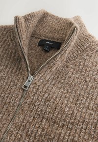 Brown zip-up sweater with a high collar, featuring textured knit fabric and silver zipper hardware. Brand label visible inside neck.
