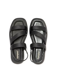 Black flat sandals with narrow fabric straps crossing over a cushioned insole. Smooth texture with a rounded toe and back ankle strap.