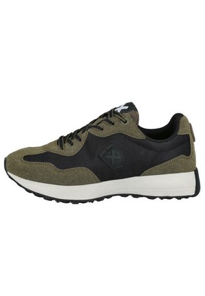 Zapatilla deportiva en verde oliva y negro, con materiales de ante y malla, punta redondeada, suela intermedia gruesa blanca y suela negra texturizada.