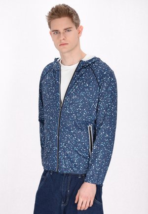 Giacca navy con un motivo a macchie in bianco e blu chiaro, dotata di zip frontale, cappuccio e tasche laterali. Tessuto con una texture liscia.