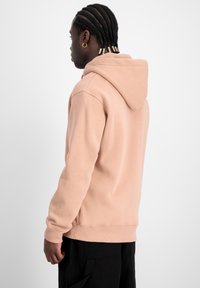 Felpa leggera rosa chiaro con una vestibilità comoda, cappuccio attaccato, polsini e orlo a coste. Texture liscia con un design minimalista, che mette in risalto la semplicità.