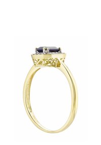 Zlatý prsteň s osemuhlovým tmavým kameňom, obklopeným dekoratívnym strieborným rámom s jemnými vyrezávanými vzormi a lesklým prsteňom.