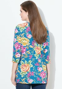 Blumenbluse in Türkis, mit bunten Rosen und Blättern. Dreiviertelärmel mit abgerundetem Saum. Weiches, leichtes Material.