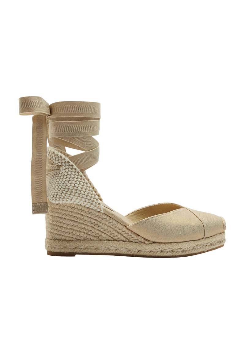Beżowe espadryle na koturnie z plecioną juteową podeszwą, materiałowym cholewką i skrzyżowanymi wstążkami przy kostce. Okrągły czubek.