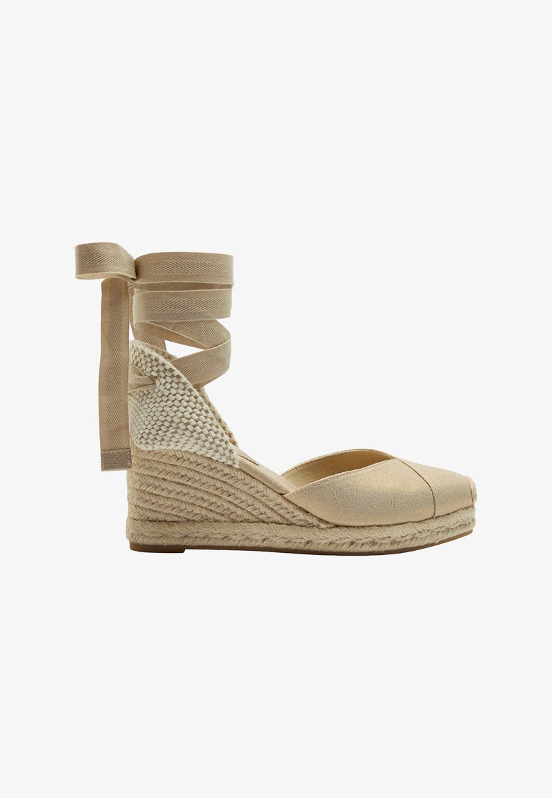 Beżowe espadryle na koturnie z plecioną juteową podeszwą, materiałowym cholewką i skrzyżowanymi wstążkami przy kostce. Okrągły czubek.