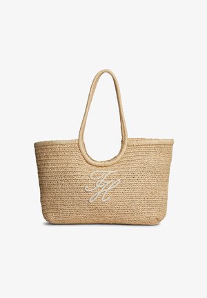 Beige geweven stro tote tas met afgeronde handvatten en witte geborduurde cursieve initialen in het midden aan de voorkant.