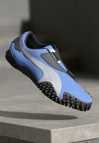 Blå og grå treningssko med et strømlinjeformet design, teksturert stoff og en robust svart såle med små pigger for grep.