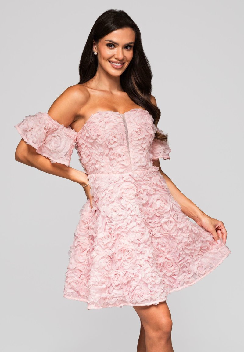 Robe rose avec des manches à volants tombantes, des appliqués floraux texturés, un corsage ajusté et une jupe évasée. Détail zippé à l'avant.