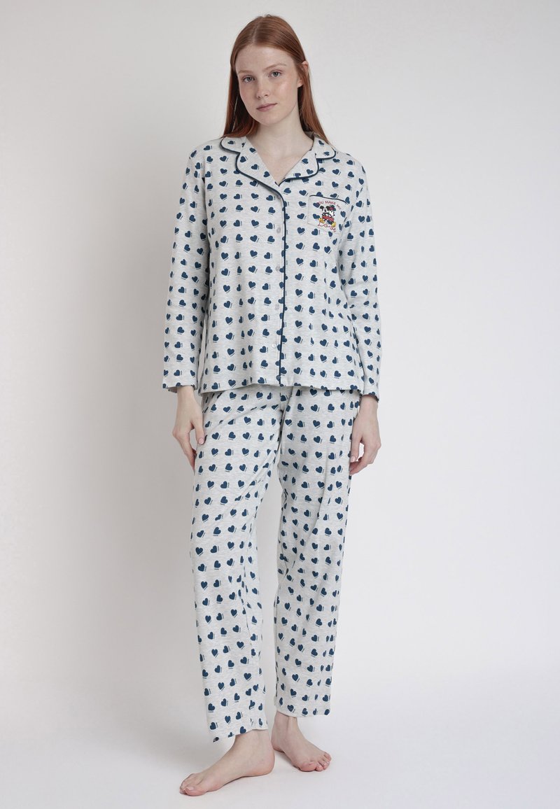 Conjunto de pijama de algodón con un fondo gris claro y pequeños patrones de corazones en azul marino, contrastado con ribetes oscuros y un bordado descriptivo.