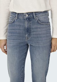Džíny z denimu světle modré barvy s rovnými nohavicemi, vybavené zipem na předním díle a zapínáním na knoflík, předními kapsami a jemným vyblednutím podél nohou.