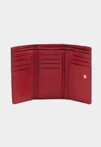 Czerwony skórzany portfel z wieloma przegródkami na karty, gładką fakturą i przeszytymi krawędziami. Ma wytłoczone logo wewnątrz.