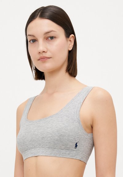 Gray cotton bralette with a scoop neckline, wide straps, and a fitted design. Features a navy logo accent on the left side.