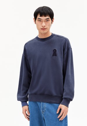 Navy blue sweatshirt with a round neck and long sleeves. Features an embroidered loop logo on the left chest. Made of soft, textured fabric.