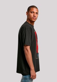 Black graphic t-shirt made of cotton, featuring a bold red design and a rectangular print. Relaxed fit and short sleeves, with a crew neckline.