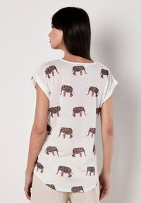 Camiseta blanca de manga corta con un patrón repetido de elefantes en intrincados diseños multicolores. Tejido suave con un corte casual.