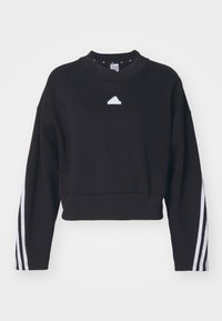 Sweatshirt nera cropped con maniche lunghe, dotata di un piccolo logo bianco sul petto e dettagli a strisce bianche lungo le maniche.