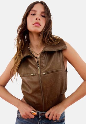 Veste sans manches en cuir marron avec un col montant, fermeture éclair à l'avant et deux poches zippées. Détails de couture côtelés en bas. Texture lisse.