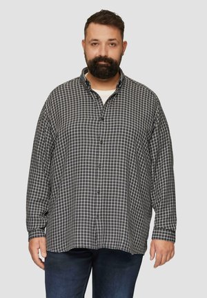 Zwart-wit geruite flanellen shirt met lange mouwen, kraag, knopenlijst en een losse pasvorm, gecombineerd met donkerblauwe jeans.