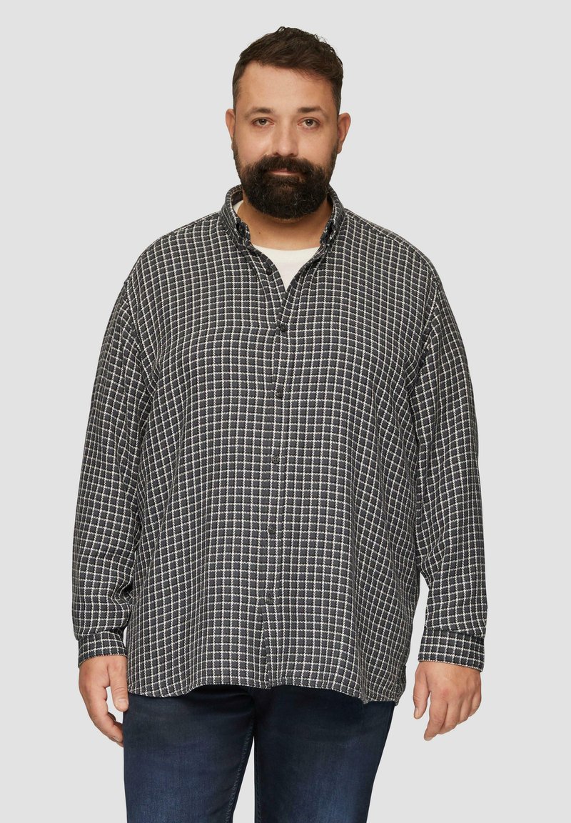 Zwart-wit geruite flanellen shirt met lange mouwen, kraag, knopenlijst en een losse pasvorm, gecombineerd met donkerblauwe jeans.