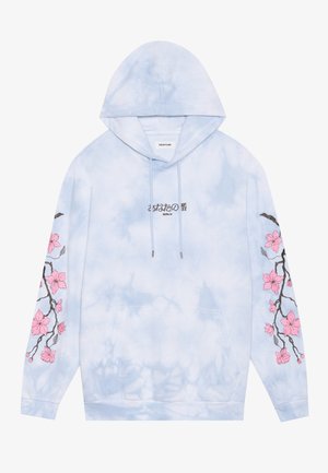 Svetlomodrá mikina s kapucňou vo farbe tie-dye, s čiernym japonským textom a nápisom "Berlín" na hrudi, a výšivkou ružovej konárika čerešne na oboch rukávoch.