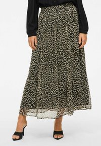 Jupe maxi en tissu transparent avec un motif léopard et un design plissé, dotée d'une taille haute. Sandales à talons noires visibles en bas.