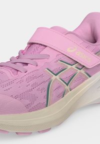 Ροζ παιδικό αθλητικό παπούτσι Asics με κορδόνια και λουράκι βέλκρο πάνω από τη γλώσσα, με μπεζ σόλα και λογότυπα στο πλάι.