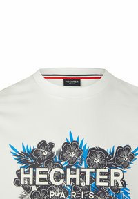 Witte katoenen tshirt met een blauw en zwart bloemenprint. Het ontwerp bevat de tekst "HECHTER PARIS" in dikke letters en een geribde halslijn.