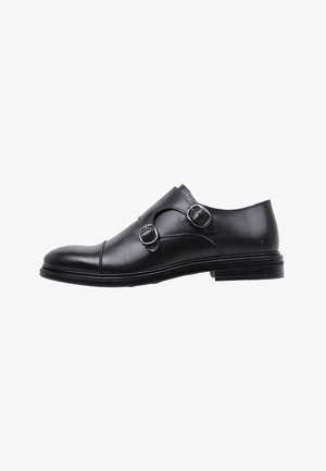 Chaussure habillée en cuir noir avec deux accents de boucles, bout rond et finition lisse. Présente un petit talon empilé et un design minimaliste.
