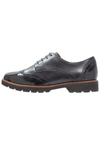 Scarpa in pelle nera con finitura lucida, caratterizzata da dettagli brogue, una punta tonda e una suola in gomma texturizzata per una migliore aderenza.