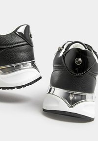 Black sneakers with textured leather and glossy accents. Features a transparent heel section and a rounded shape. White rubber outsole.