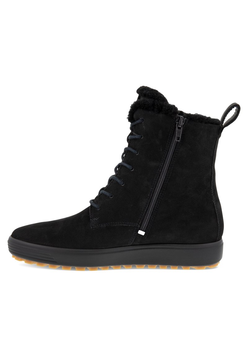 Botas negras de ante hasta el tobillo con un cuello de peluche, lazo frontal y cremallera lateral. Tienen suela de tracción de goma y un logo mínimo.