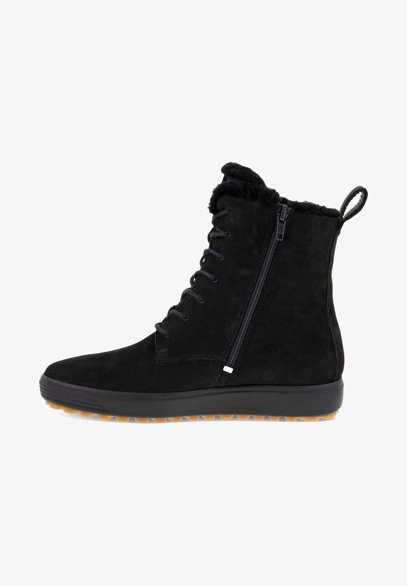 Botas negras de ante hasta el tobillo con un cuello de peluche, lazo frontal y cremallera lateral. Tienen suela de tracción de goma y un logo mínimo.