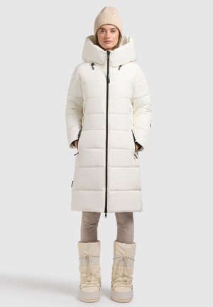 White puffer coat with large hood, zip closure, and front pockets, paired with beige snow boots featuring laces and a textured finish.