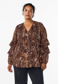 Brown snake print blouse with a V-neck, ruffled sleeves, and button details, made from a lightweight material. Paired with black pants.