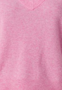 Mjukt rosa stickad V-ringad tröja med ribbat fåll och subtil melerad struktur.