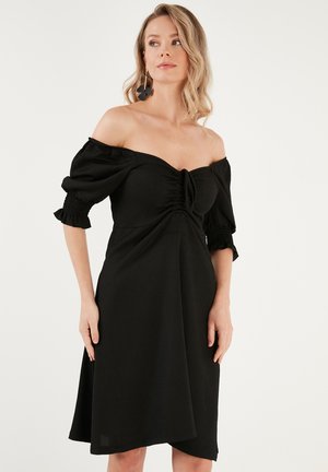 Black off-the-shoulder dress with short puff sleeves, gathered detailing at the bust, and a flared skirt, made from a textured fabric.
