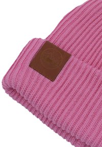 Różowa dziana czapka z prążkowanym wzorem i brązową skórzaną metką z okrągłym logo. Materiał wydaje się miękki i ciepły.