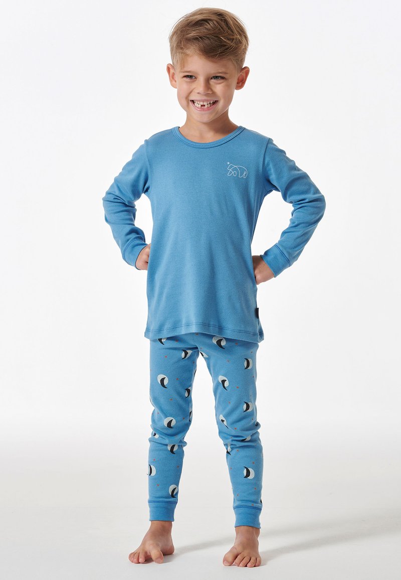 Haut de pyjama bleu à manches longues avec un motif d'ours ; pantalon de pyjama bleu assorti avec des motifs de lunes et des accents rouges. Tissu doux et confortable.