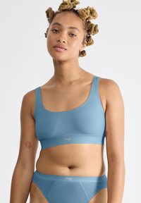 Vaaleansininen saumaton bralette ja yhteensopiva alaosa, valmistettu sileästä kankaasta. Ominaisuudet leveät hihnat ja minimalistinen muotoilu, jossa on hienovarainen logo.