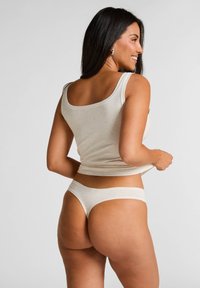 Ensemble de débardeur beige et de culotte string en tissu doux et extensible ; présente un décolleté arrondi classique et un design minimaliste.