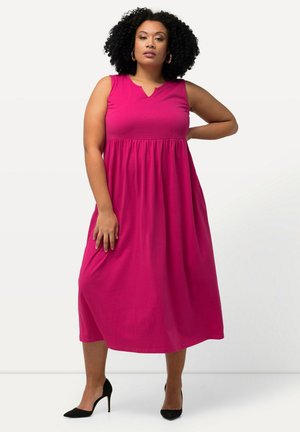 Magenta ilman hihoja mekko, jossa on V-pääntie, kerääntynyt vyötärö ja virtaava hame. Tyylitelty mustilla korkokengillä. Tasainen kankaan rakenne.