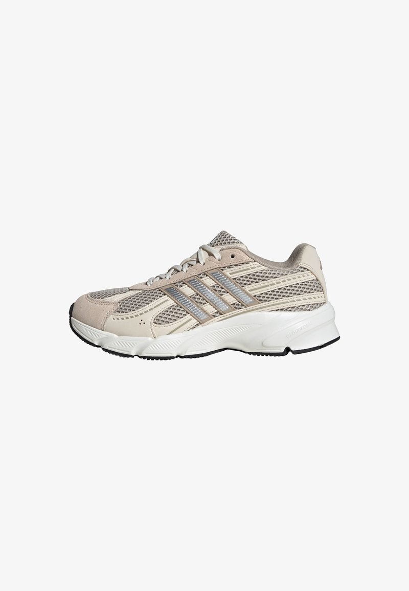 Baskets de sport beige clair et gris avec panneaux en mesh, design latéral à trois bandes, semelle blanche rembourrée, et semelle extérieure noire.