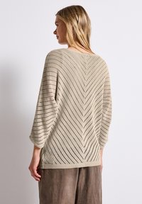 Beige knitted sweater with a chevron pattern, loose fit, ¾ sleeves, and ribbed hem. Designed with an open weave texture for breathability.