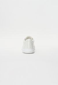 Sneakers bianchi con finitura in pelle liscia, punta rotonda, cuciture sottili e suola imbottita. Vista posteriore che mette in evidenza il design minimalista.