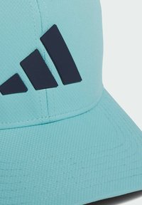 Světlomodrá čepice z texturované látky s rovným kšiltem a třemi tmavě modrými diagonálními pruhy. Detaily doplňují viditelné švy.