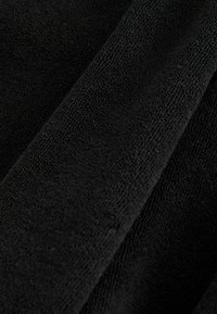Črn teksturiran material, mehak površinski otip z prijetnim občutkom, z gladkim zaključkom in subtilnim vzorcem tkanja, položen v gube.