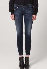 Smaljeans i mörk denim med medelhög midja, subtila blekningar, framfickor och en kroppsnära ankellång design.