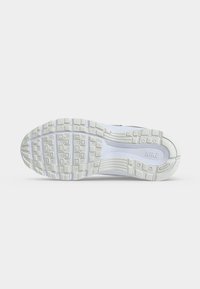 Λευκή σόλα παπουτσιού Nike για τρέξιμο με υφή για καλύτερη πρόσφυση και ορατό λογότυπο Nike στην περιοχή του μέσου ποδιού σε απλό φόντο.