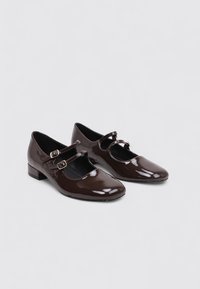 Zapatos Mary Jane de charol marrón con dos correas ajustables, punta redonda y un bajo tacón cuadrado para mayor comodidad.