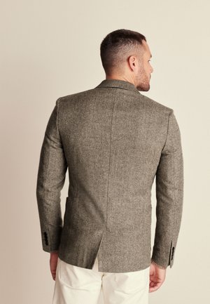 Blazer grigio a spina di pesce con vestibilità sartoriale, spalle strutturate e retro con spacco, dotato di bottoni neri sulle maniche.